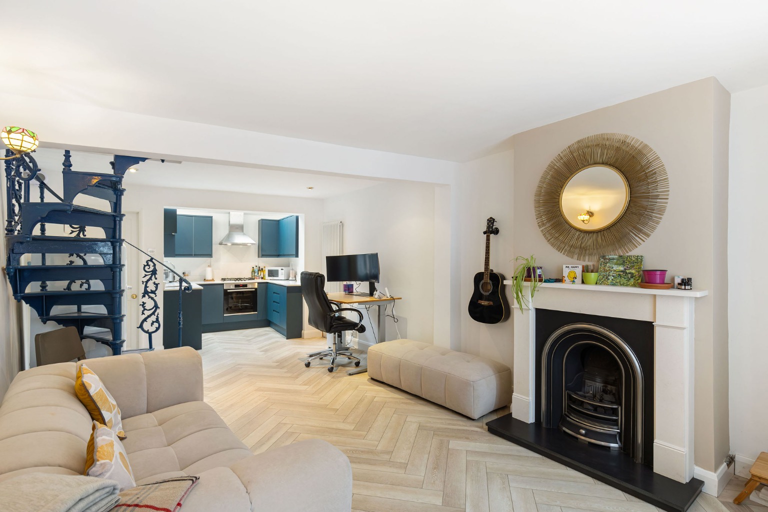 Living room with a fireplace, gold mirror and blue spiral staircase